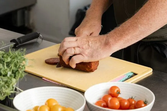 cutting salami on yellow plastic cutting board- best cutting board for each type of food