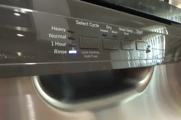 Close-up of a stainless steel dishwasher control panel showing the rinse cycle light turned on.