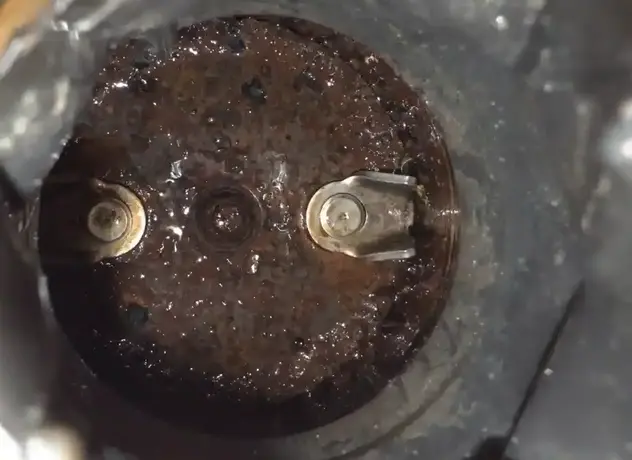Close-up of a garbage disposal chamber showing blades and leftover food buildup inside the unit in a result of forbidden things that we should never put in your garbage disposal