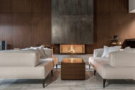 Elegant modern living room featuring cream sofas, a sleek wood coffee table, and a striking floor-to-ceiling fireplace, serving as the dramatic focal point of the space.