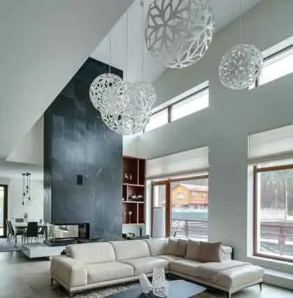 Spacious modern living room with a white sectional sofa, tall black accent fireplace, and eye-catching spherical chandeliers, creating a bold focal point in the open-concept space.