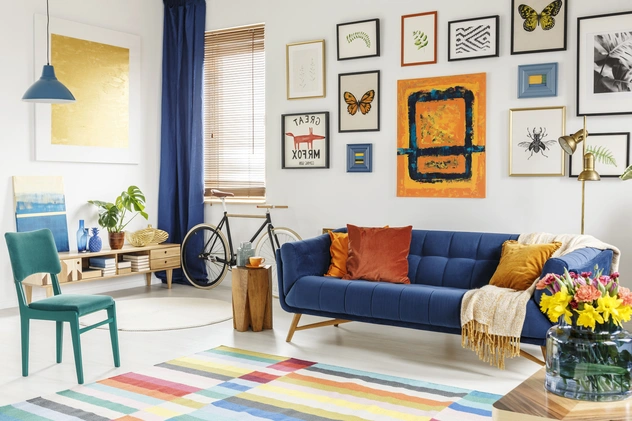 Maximalism Decor in living room with vibrant colorful rug, wall art gallery , blue sofa