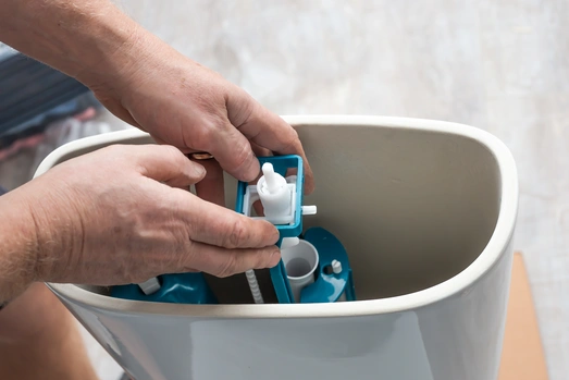 a mn repairing internal part of toilet tank 